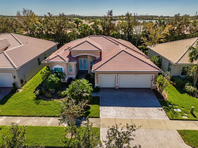 4977 Sapphire Sound Dr, Wimauma, FL 33598 - mediterranean / spanish-style home with decorative driveway, a tiled roof, an attached garage, and stucco siding