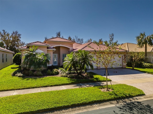4977 Sapphire Sound Dr, Wimauma, FL 33598 - mediterranean / spanish-style home featuring decorative driveway, a tile roof, a garage, stucco siding, and a front yard