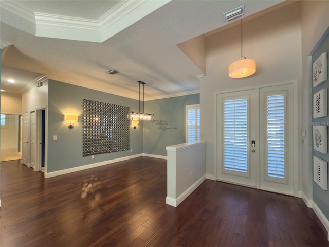 entrance foyer featuring a textured ceiling, ornamental molding, and dark wood-type flooring