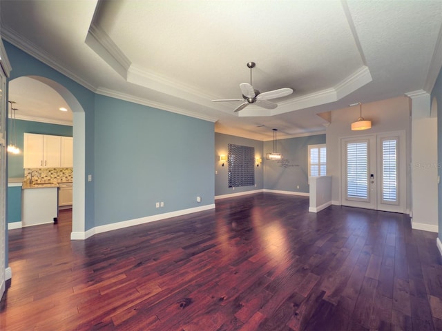 unfurnished living room with ceiling fan, french doors, dark hardwood / wood-style flooring, crown molding, and a tray ceiling