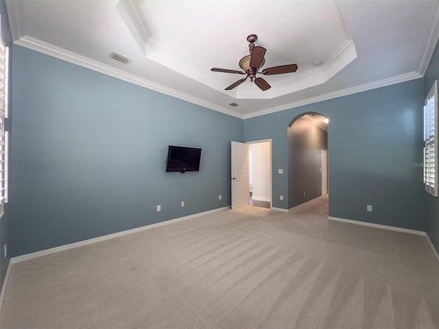 carpeted empty room featuring ceiling fan, a raised ceiling, and crown molding