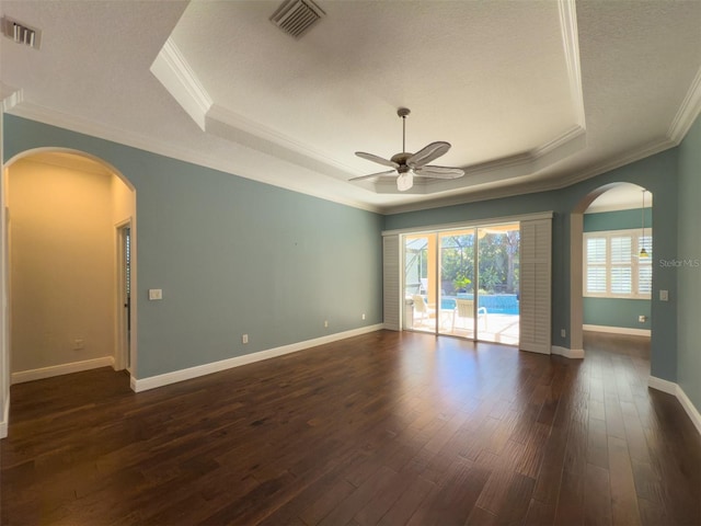 empty room featuring ornamental molding, a textured ceiling, a raised ceiling, ceiling fan, and dark hardwood / wood-style floors