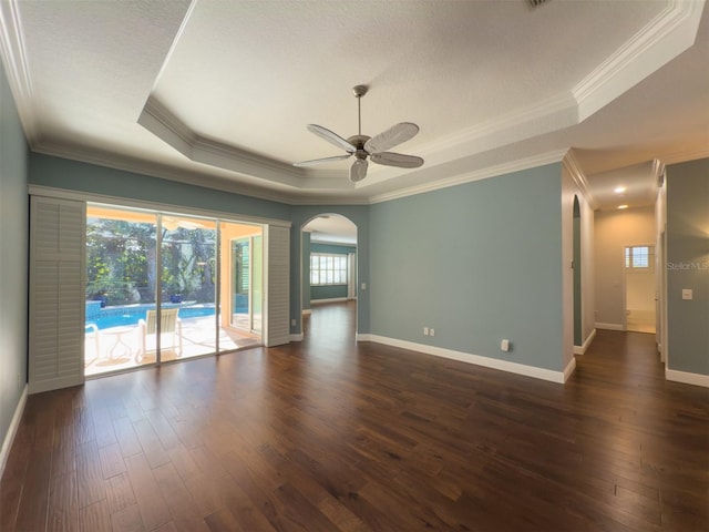 unfurnished room featuring dark hardwood / wood-style floors, ceiling fan, ornamental molding, and a tray ceiling