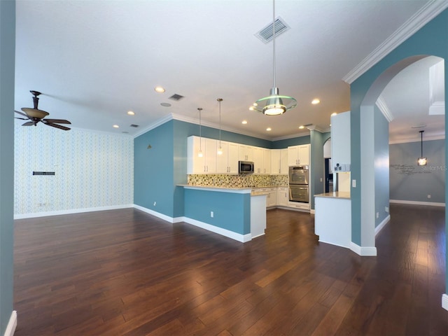 kitchen featuring white cabinets, appliances with stainless steel finishes, decorative light fixtures, dark hardwood / wood-style flooring, and kitchen peninsula