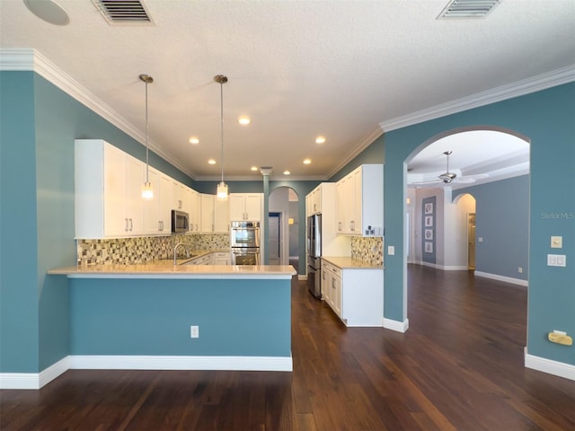 kitchen featuring white cabinets, hanging light fixtures, appliances with stainless steel finishes, dark hardwood / wood-style flooring, and kitchen peninsula