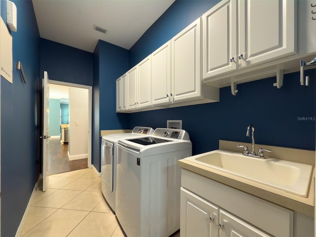 laundry area featuring cabinets, light tile patterned floors, sink, and washing machine and clothes dryer