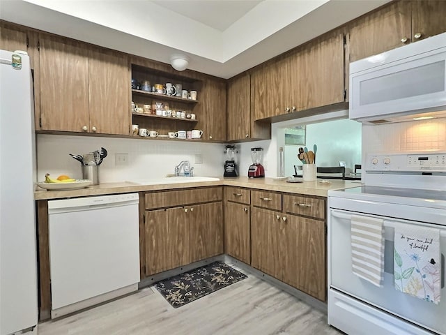 kitchen with light hardwood / wood-style flooring, white appliances, tasteful backsplash, and sink