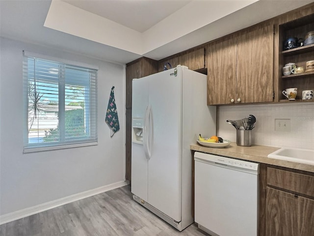 kitchen with backsplash, light hardwood / wood-style floors, and white appliances