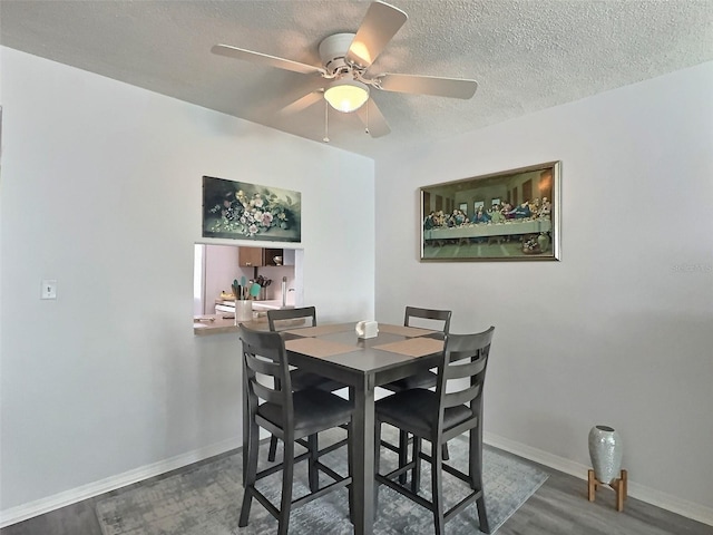 dining room featuring a textured ceiling, wood-type flooring, and ceiling fan