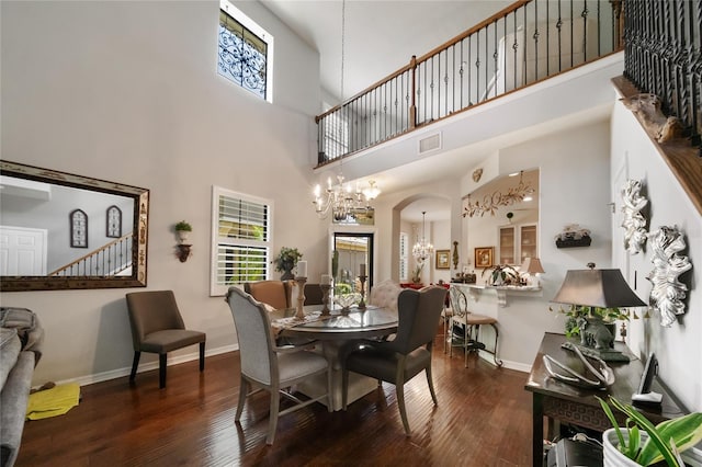 dining space featuring a notable chandelier, a towering ceiling, and dark wood-type flooring