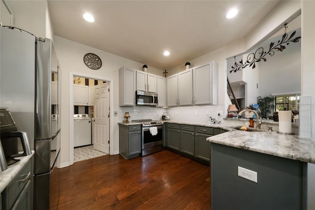 2539 Silverback Ct, Palm Harbor, FL 34684 - kitchen featuring gray cabinets, backsplash, a peninsula, washer / clothes dryer, and stainless steel appliances