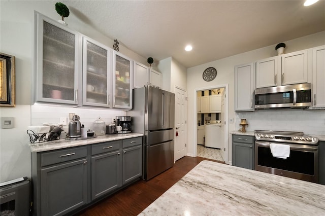 kitchen featuring gray cabinetry, decorative backsplash, light stone counters, and appliances with stainless steel finishes