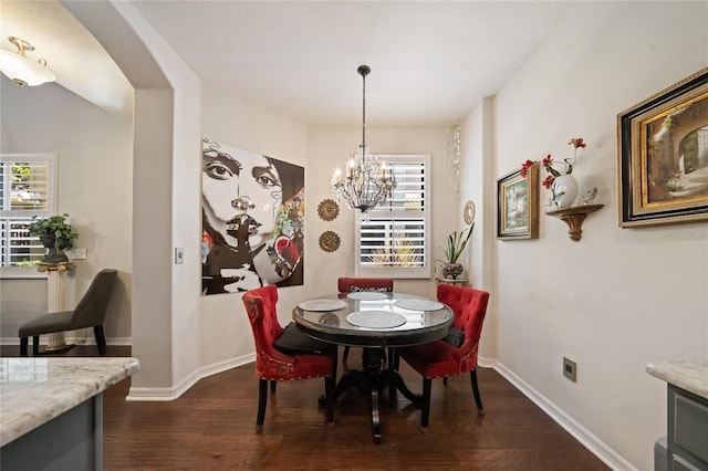 2539 Silverback Ct, Palm Harbor, FL 34684 - dining room featuring dark wood-type flooring, arched walkways, baseboards, and a notable chandelier
