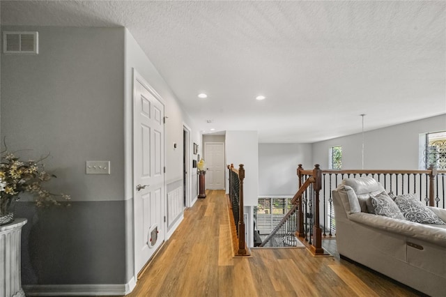 2539 Silverback Ct, Palm Harbor, FL 34684 - corridor featuring an upstairs landing, recessed lighting, a textured ceiling, light wood-style floors, and visible vents