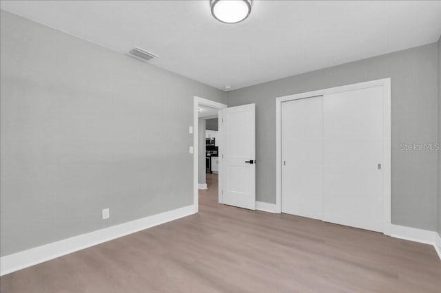 unfurnished bedroom with wood-type flooring and a closet