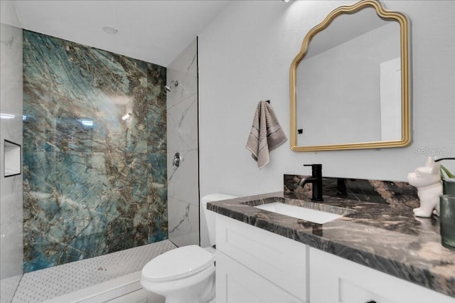 bathroom with a tile shower, vanity, and toilet