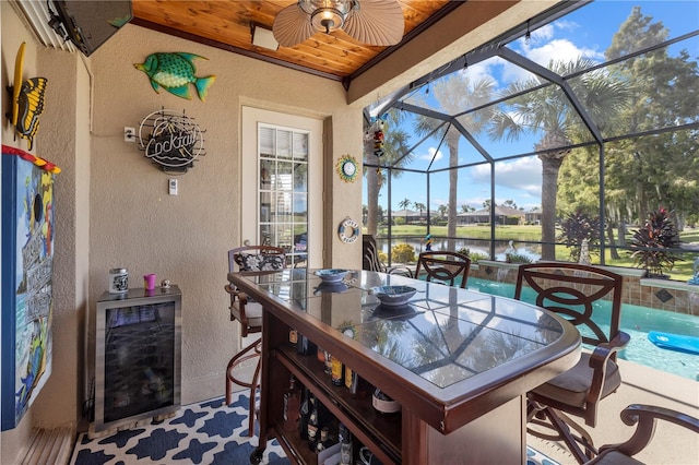 view of patio / terrace with a water view, wine cooler, ceiling fan, and a lanai