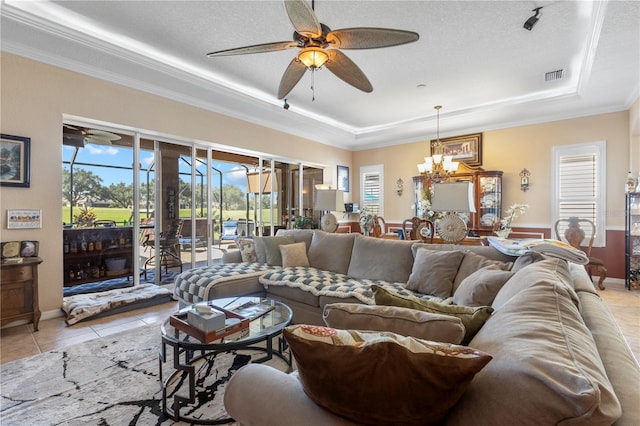 tiled living room with ceiling fan with notable chandelier, a textured ceiling, a tray ceiling, and ornamental molding