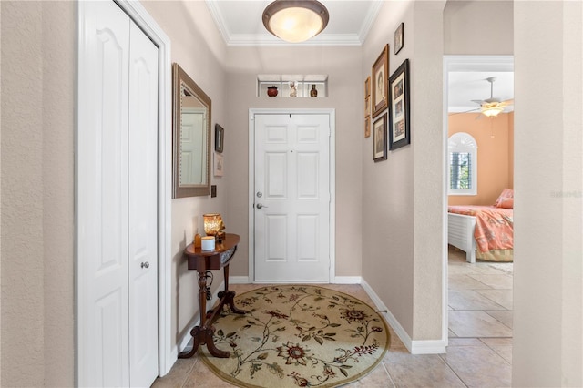 tiled entrance foyer featuring ceiling fan and crown molding