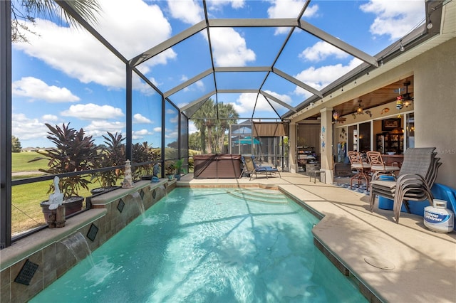 view of pool with ceiling fan, a lanai, a hot tub, pool water feature, and a patio area