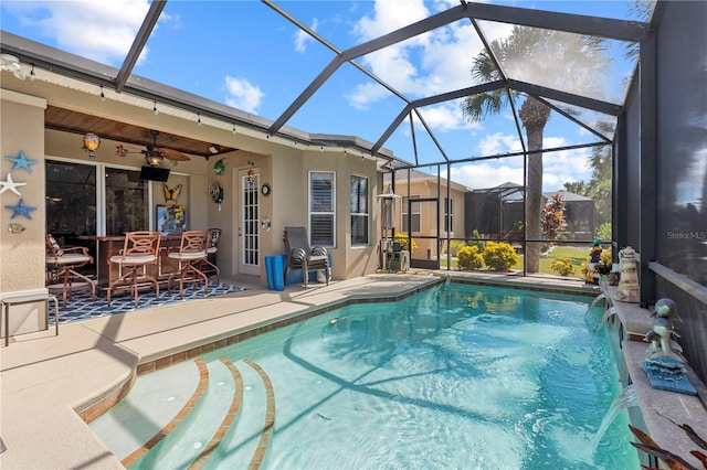 view of swimming pool featuring pool water feature, glass enclosure, a patio, and ceiling fan