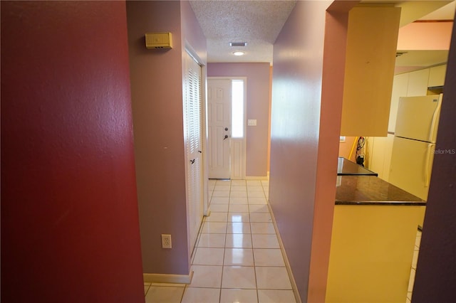 corridor featuring a textured ceiling and light tile patterned floors