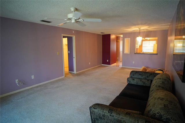 living room featuring a textured ceiling, ceiling fan, and light colored carpet