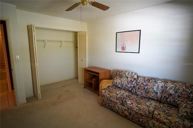 living area featuring ceiling fan, light colored carpet, and a textured ceiling