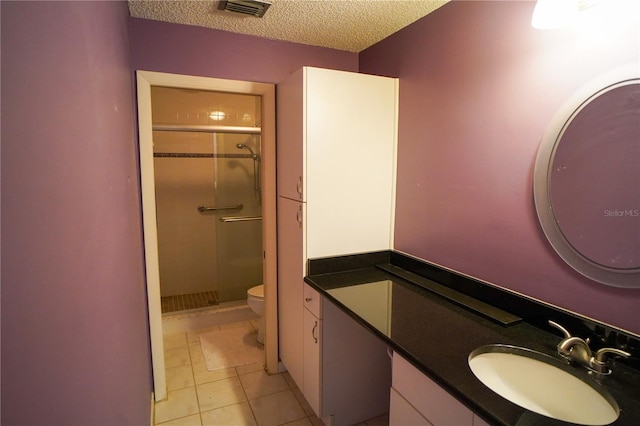 bathroom featuring a textured ceiling, a shower with door, vanity, and toilet