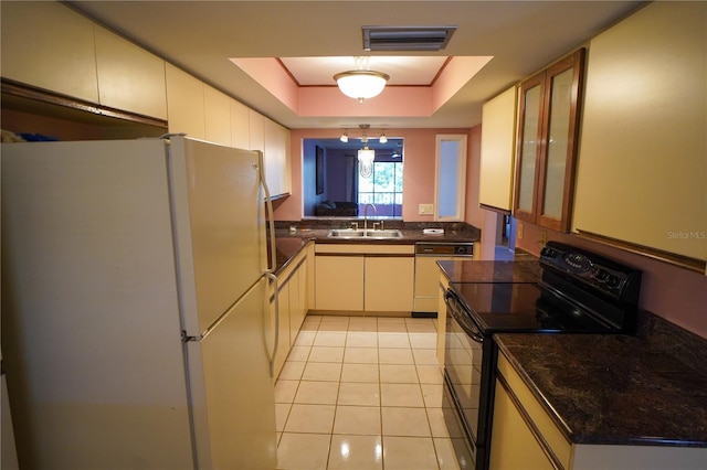 kitchen featuring a sink, white appliances, dark countertops, and a raised ceiling