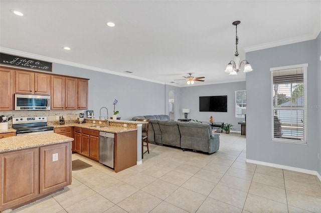 kitchen featuring hanging light fixtures, ceiling fan with notable chandelier, kitchen peninsula, light stone countertops, and stainless steel appliances