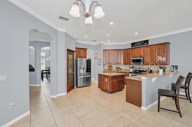 kitchen with kitchen peninsula, ornamental molding, stainless steel appliances, a notable chandelier, and light stone countertops