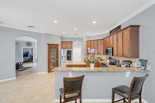 kitchen featuring decorative backsplash, ornamental molding, stainless steel appliances, and light stone counters