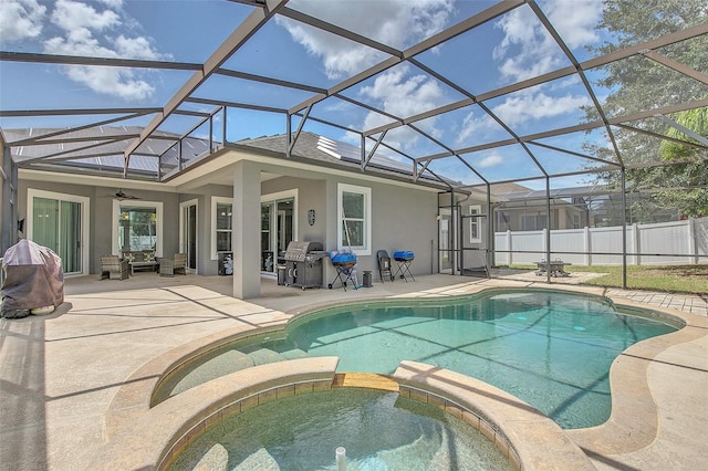 view of swimming pool with a patio, an in ground hot tub, ceiling fan, and glass enclosure