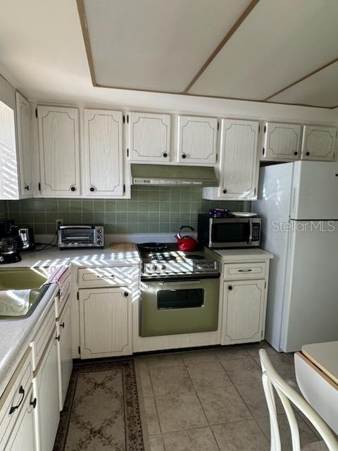 kitchen featuring white cabinets, light tile patterned floors, appliances with stainless steel finishes, and tasteful backsplash