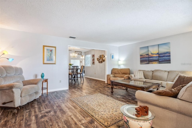 living room featuring a chandelier, a textured ceiling, and dark wood-type flooring