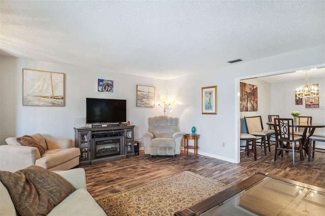 living room with an inviting chandelier, a textured ceiling, and dark wood-type flooring