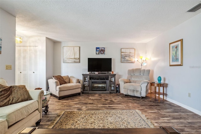 living room featuring a textured ceiling, a fireplace, and dark wood-type flooring