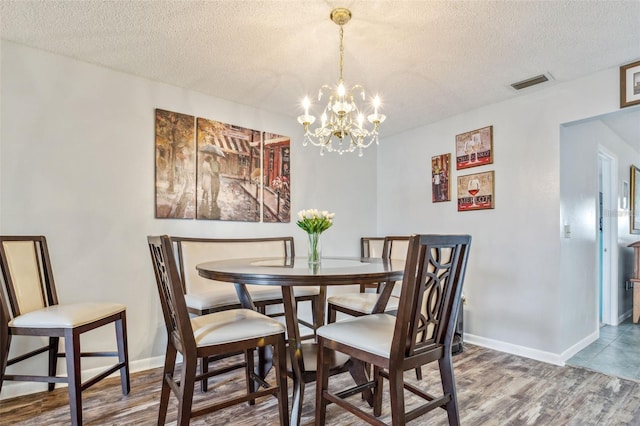 dining space with an inviting chandelier, wood-type flooring, and a textured ceiling