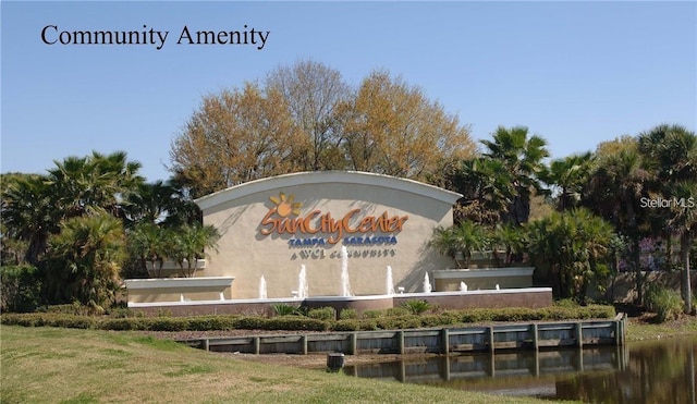 community sign featuring a lawn and a water view