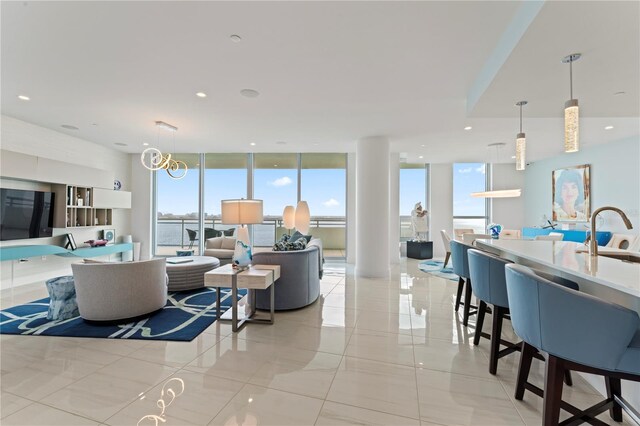 living room featuring a wall of windows, light tile patterned flooring, and sink