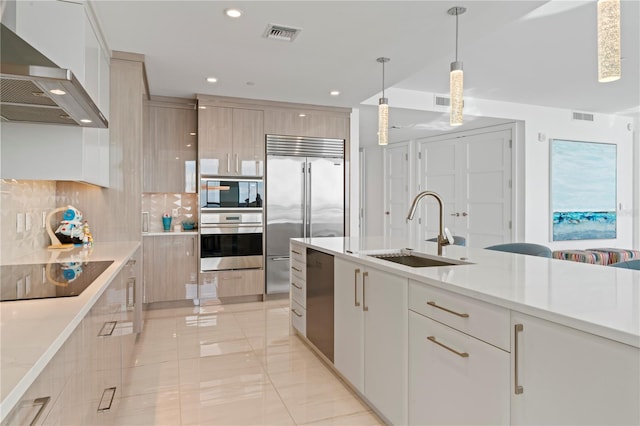 kitchen with sink, wall chimney exhaust hood, decorative backsplash, black appliances, and decorative light fixtures