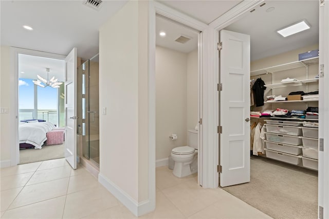 bathroom featuring tile patterned flooring, toilet, and a shower with shower door