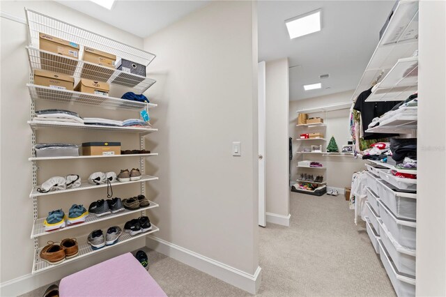 walk in closet with light carpet