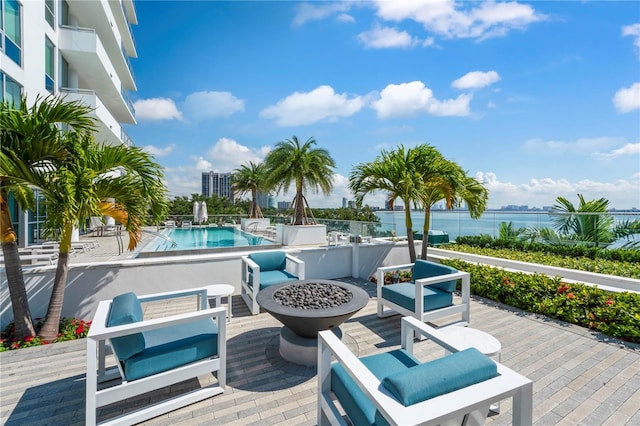 wooden deck featuring a patio, a water view, a fire pit, and a community pool