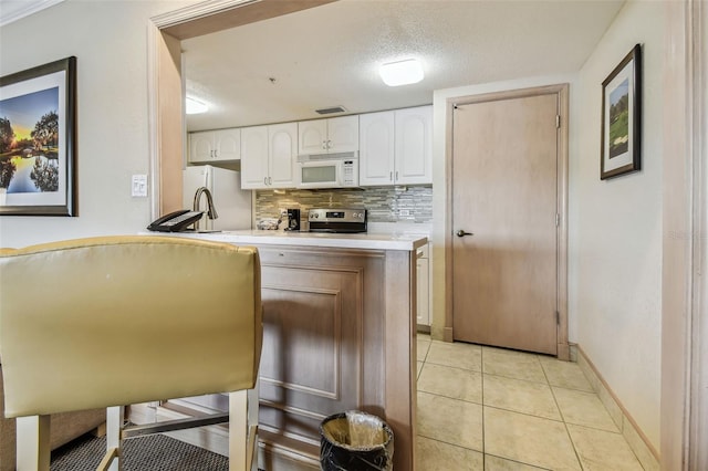 36750 US Highway 19 N Unit 04308, Palm Harbor, FL 34684 - kitchen with white cabinets, light countertops, light tile patterned floors, white appliances, and decorative backsplash