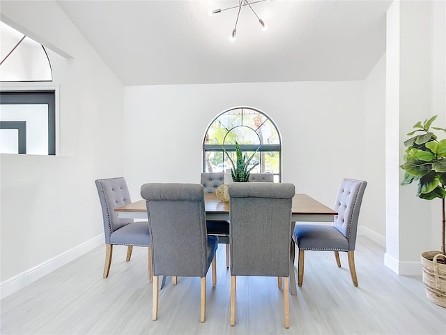 dining room with an inviting chandelier, light hardwood / wood-style flooring, and lofted ceiling