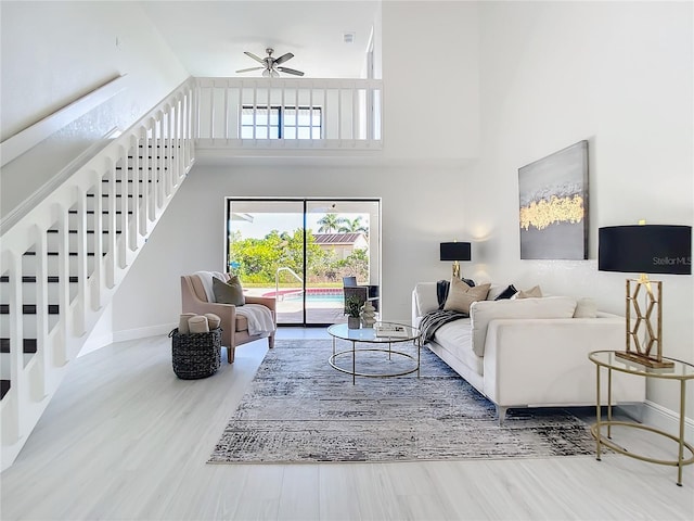 living room with ceiling fan, hardwood / wood-style flooring, and a towering ceiling