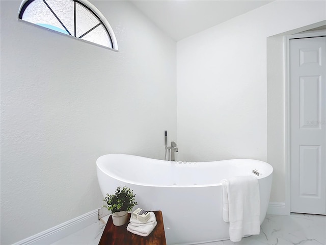 bathroom featuring a washtub and vaulted ceiling