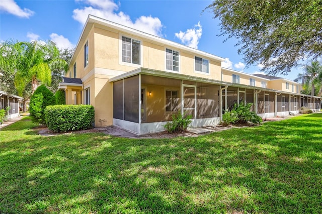 rear view of property with a sunroom and a lawn